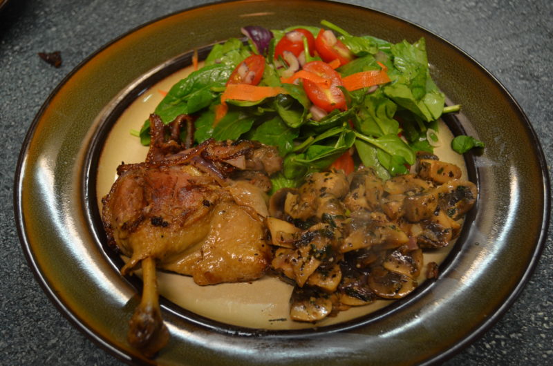 duck confit with vegetables on ceramic plate